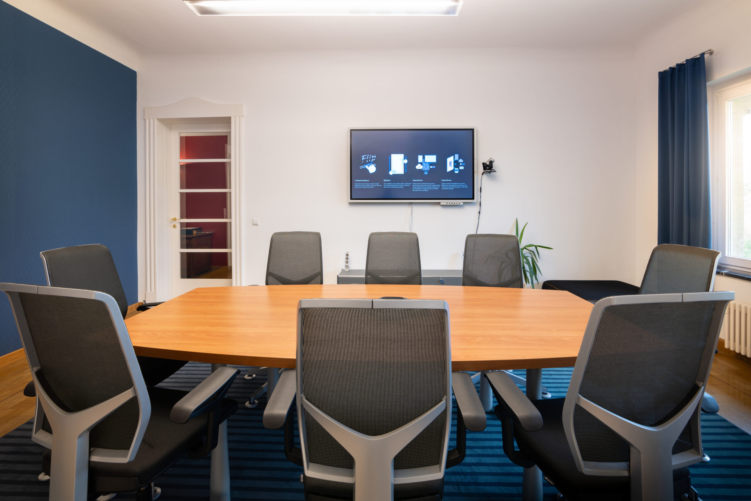 Besprechungsraum Kanzlei mit 8 Stuehlen und Flatscreen an Wand